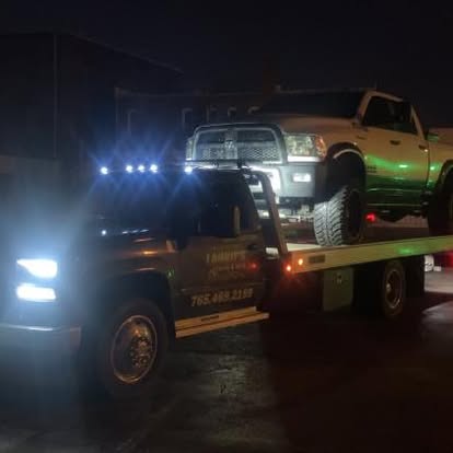 Laurie’s flatbed transporting a vehicle at night.